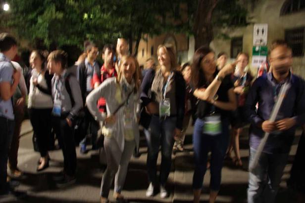 Eine Gruppe von Menschen steht abends im Freien.