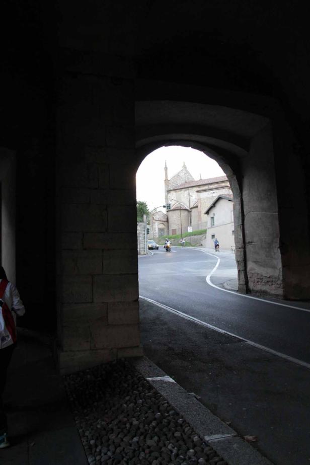 Blick durch einen Torbogen auf eine Straße mit einem Gebäude im Hintergrund.