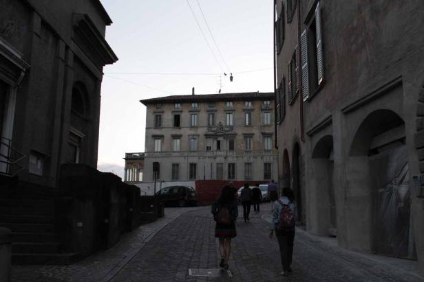 Zwei Frauen gehen eine Kopfsteinpflasterstraße in einer italienischen Stadt entlang.