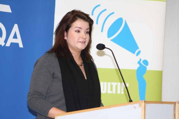 Eine Frau spricht bei einer Präsentation am Rednerpult.