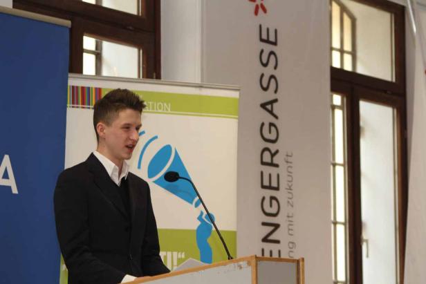 Ein junger Mann hält eine Rede an einem Rednerpult.