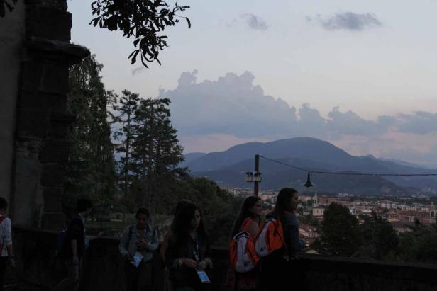Eine Gruppe von Menschen blickt auf eine Stadt vor einer Bergkulisse.