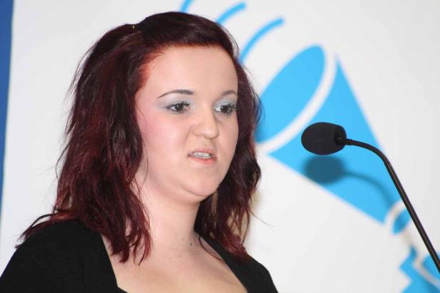 Eine Frau mit roten Haaren spricht in ein Mikrofon.