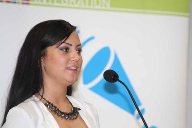 Eine Frau spricht bei einer Veranstaltung am Mikrofon.