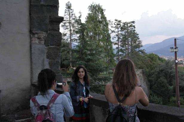 Drei junge Frauen genießen die Aussicht von einer steinernen Mauer und machen Fotos.