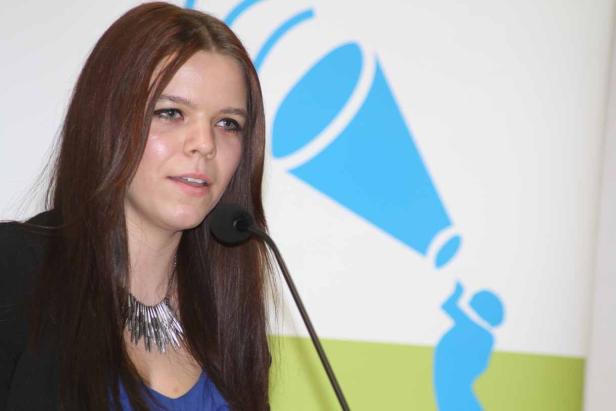 Eine Frau spricht bei einer Veranstaltung in ein Mikrofon.