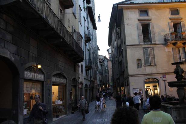 Blick in eine belebte Gasse in einer italienischen Stadt mit einer Trattoria.