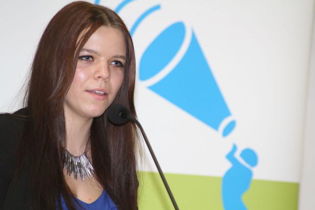 Eine Frau spricht bei einer Veranstaltung in ein Mikrofon.