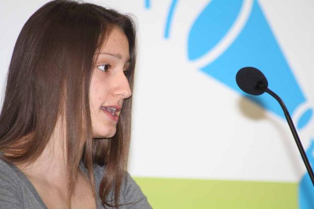 Eine junge Frau spricht an einem Mikrofon.