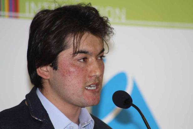 Ein Mann spricht bei einer Konferenz in ein Mikrofon.