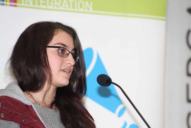 Eine junge Frau mit Brille spricht an einem Mikrofon.