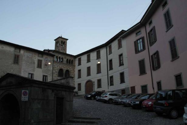 Ein Platz mit alten Gebäuden und geparkten Autos in einer italienischen Stadt.