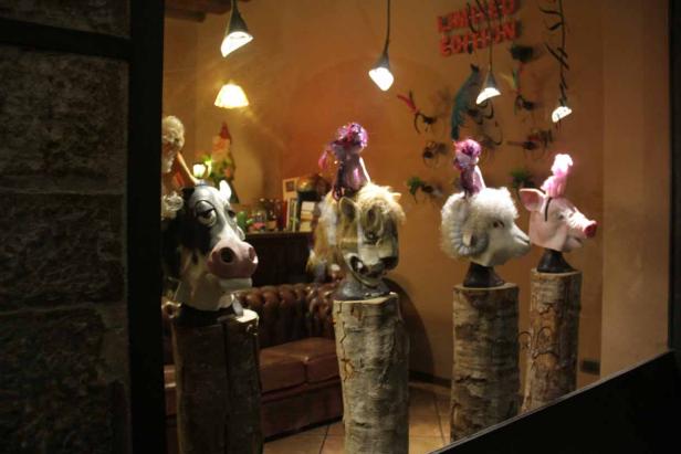 Ein Schaufenster mit Tiermasken auf Baumstümpfen, darunter eine Kuh, ein Löwe, ein Schaf und ein Schwein.