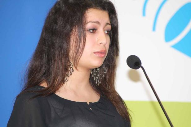 Eine Frau spricht bei einer Veranstaltung in ein Mikrofon.