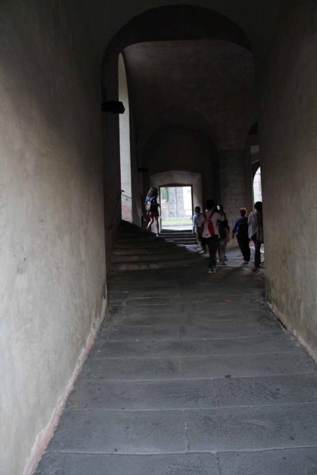 Eine Gruppe von Menschen geht durch einen dunklen Torbogen.