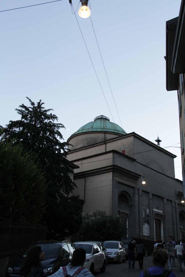 Eine Kirche mit grüner Kuppel und Straßenlaternen in einer italienischen Stadt.