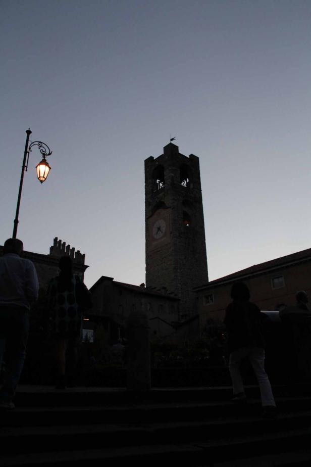 Eine abendliche Aufnahme eines Glockenturms in einer italienischen Stadt.