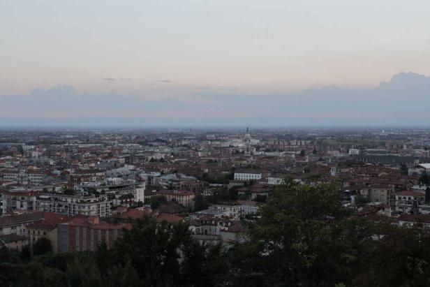 Blick über eine Stadt mit vielen Gebäuden und Bäumen im Abendlicht.