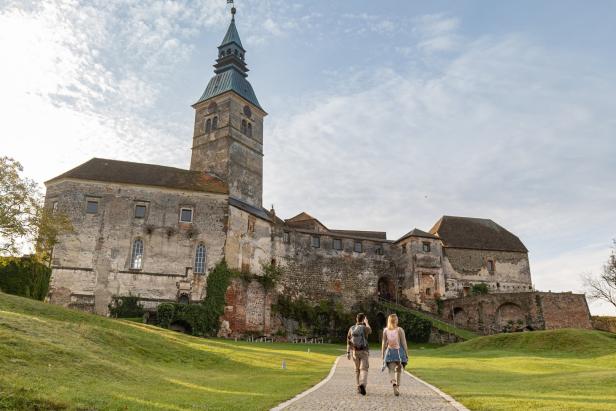Ein Paar geht auf einem Weg zu einer alten Burg mit einem Turm.