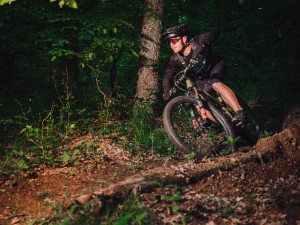 Ein Mountainbiker fährt einen steilen, bewaldeten Pfad hinunter.