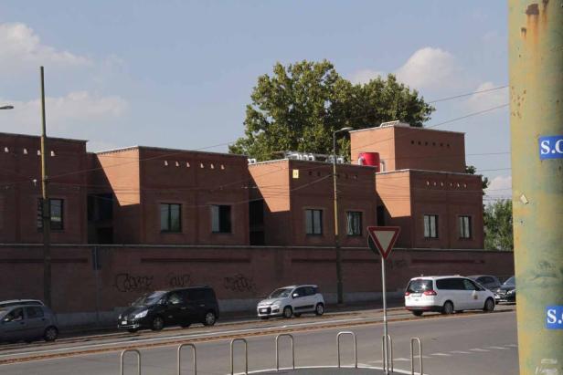 Mehrere Autos fahren vor einem Backsteingebäude mit Graffiti.