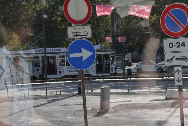 Eine Straßenansicht in Mailand mit Verkehrsschildern und einer Straßenbahn.