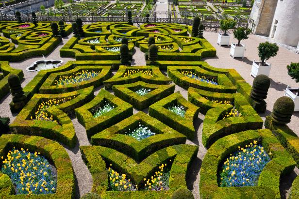 Ein formaler Garten mit geometrischen Hecken und bunten Blumenbeeten.