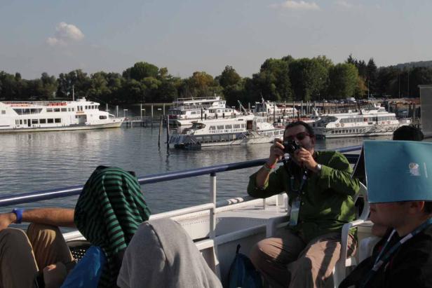 Ein Mann fotografiert vom Deck eines Schiffes aus andere Schiffe im Hafen.