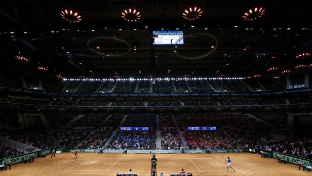 Tennismatch in einer Arena mit Zuschauern auf den Rängen.