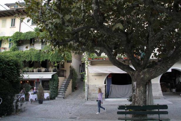 Eine Frau geht an einem Café in einer malerischen Gasse vorbei.