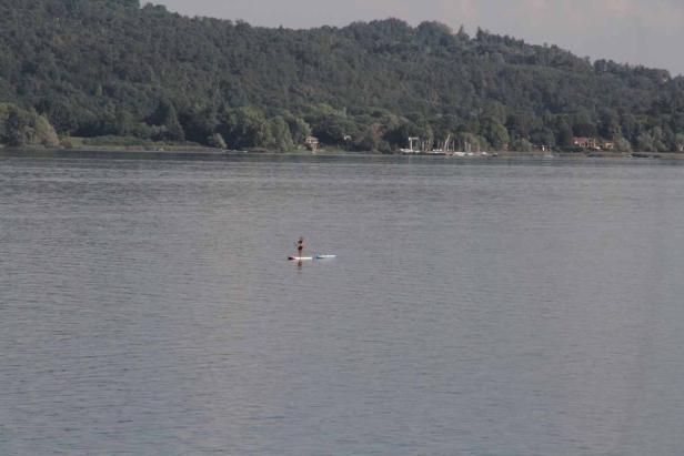 Eine Person steht auf einem Stand-Up-Paddleboard auf einem See.