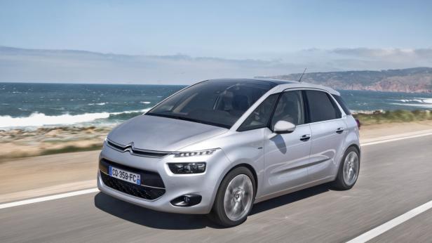 Ein silberner Citroën C4 Picasso fährt auf einer Küstenstraße.