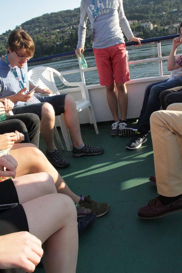 Eine Gruppe von Menschen sitzt und steht auf einem Schiff.