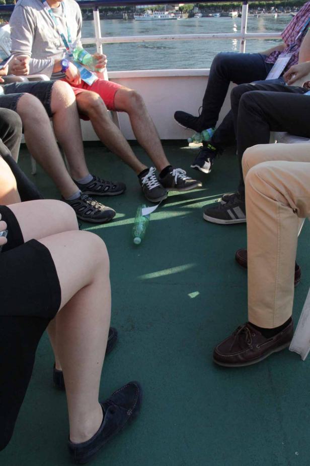 Menschen sitzen auf einem Boot, eine leere Plastikflasche liegt auf dem Boden.