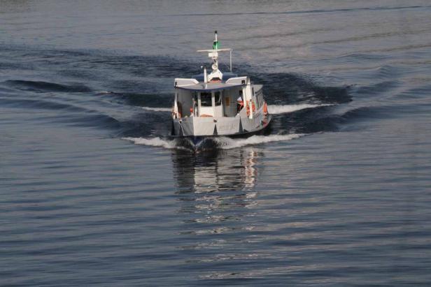 Ein kleines Passagierschiff fährt auf dem Wasser und hinterlässt Wellen.