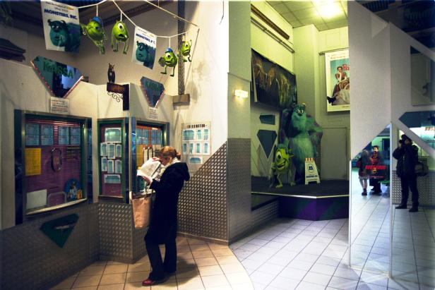 Eine Frau liest vor dem Ticketschalter eines Kinos, das mit „Monsters, Inc.“-Dekorationen geschmückt ist.