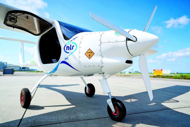 Ein weißes Kleinflugzeug mit Elektroantrieb steht auf einem Flugfeld.