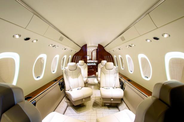 Innenansicht eines Privatjets mit Ledersitzen und ovalen Fenstern.
