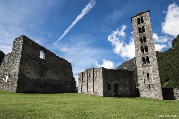 Die Ruinen einer alten Kirche mit einem hohen Turm unter blauem Himmel.