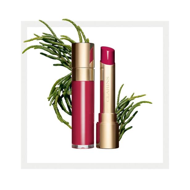 Ein roter Clarins Lippenstift und Lipgloss mit grünen Zweigen im Hintergrund.
