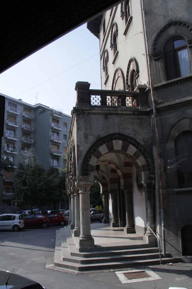 Ein überdachter Gang mit Säulen vor einem Gebäude.