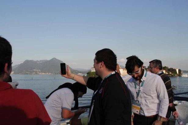 Eine Gruppe von Menschen macht Fotos von einem See mit Bergen im Hintergrund.