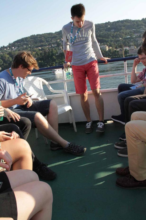 Eine Gruppe junger Leute sitzt und steht auf einem Ausflugsschiff.