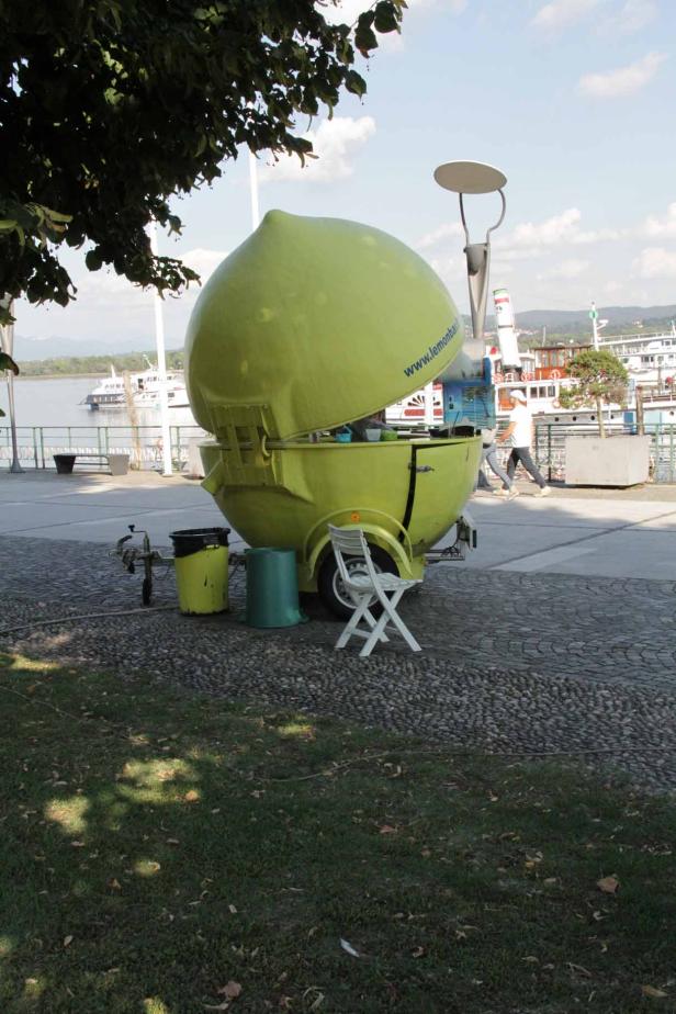 Ein limonenförmiger Verkaufsstand steht an einer Uferpromenade.
