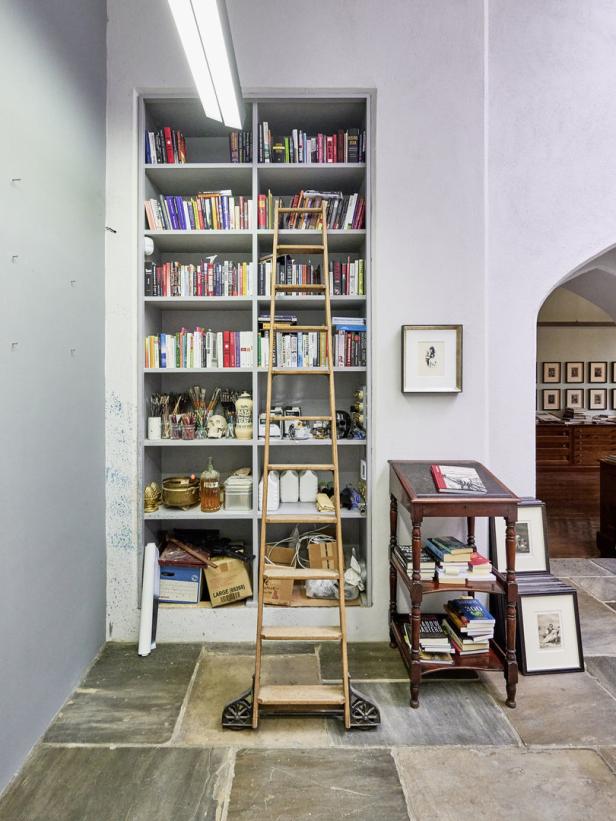 Ein Bücherregal mit einer Leiter davor in einem Arbeitszimmer.
