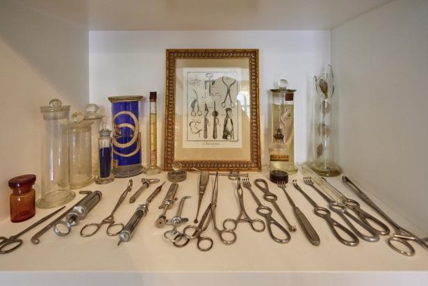 Eine Sammlung von alten medizinischen Instrumenten und Präparaten in Gläsern auf einem Regal.