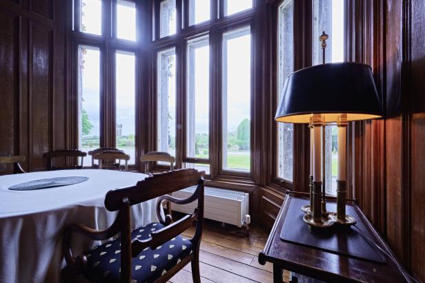 Ein Esszimmer mit einem Tisch, Stühlen und einer Stehlampe mit Blick auf einen Garten.