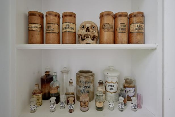 Ein Regal mit alten Apothekergefäßen und einem menschlichen Schädel.