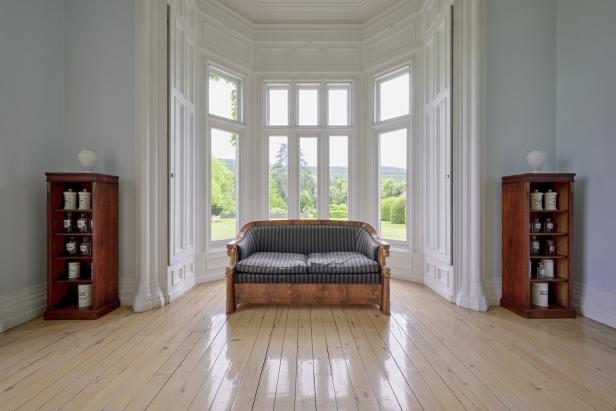 Ein Zimmer mit einem Sofa vor einem großen Fenster und zwei Regalen an den Seiten.