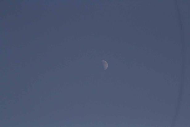 Eine Mondsichel vor einem blauen Himmel.